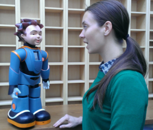 Female looks at a humanoid robot that stands on a table