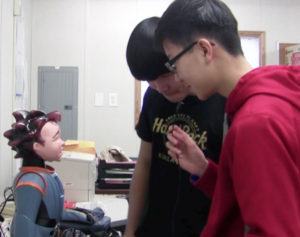 Two people look at humanoid robot